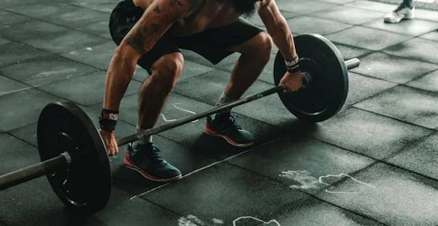 Mann setzt im Fitnessstudio zum Heben einer beladenen Langhantel an